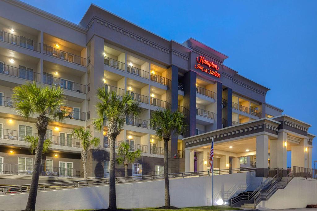 a hotel building with palm trees in front of it at Hampton Inn & Suites Galveston in Galveston