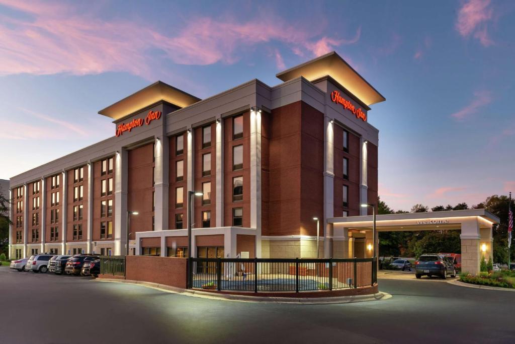 Hampton Inn Greensboro Airport في جرينسبورو: تقديم مبنى للفندق مع وجود مواقف للسيارات