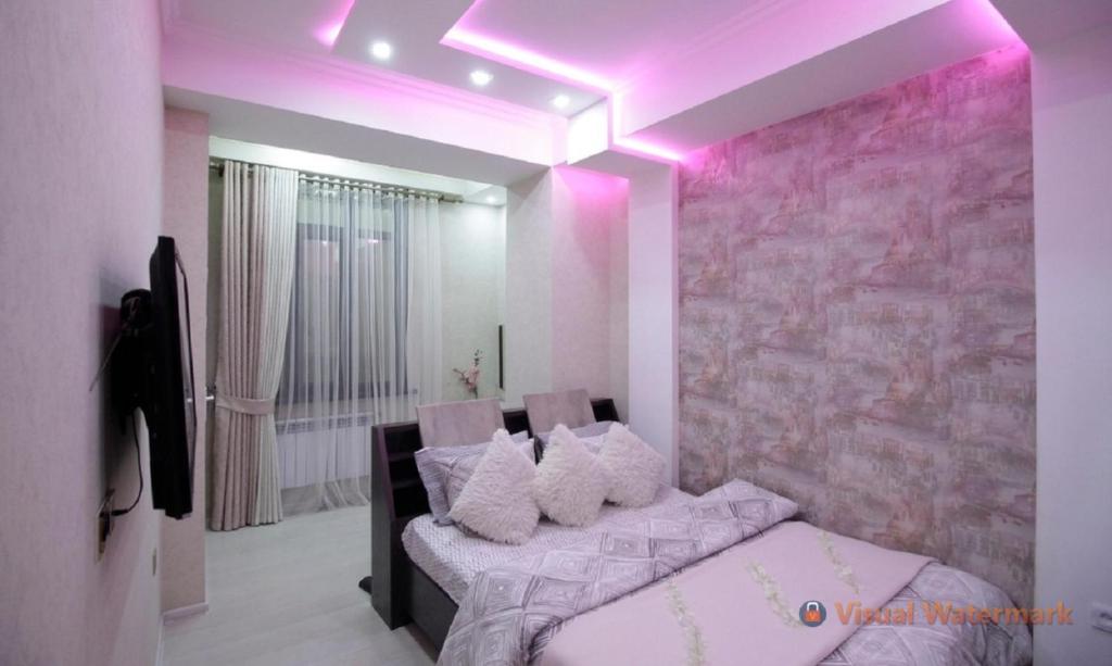 Квартира с хорошей энергетикой في دوسهانبي: غرفة نوم مع إضاءة وردية وسرير مع وسائد
