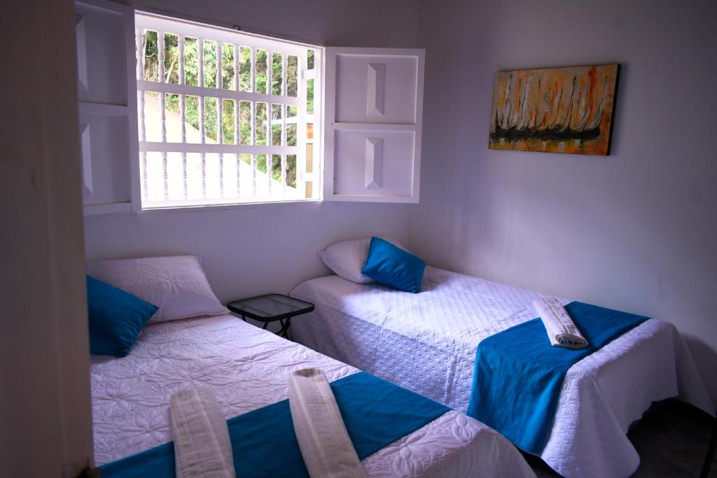 Habitación con 2 camas y ventana en Preciosa finca en el peñol de Guatapé con piscina y jacuzzi, en Guatapé