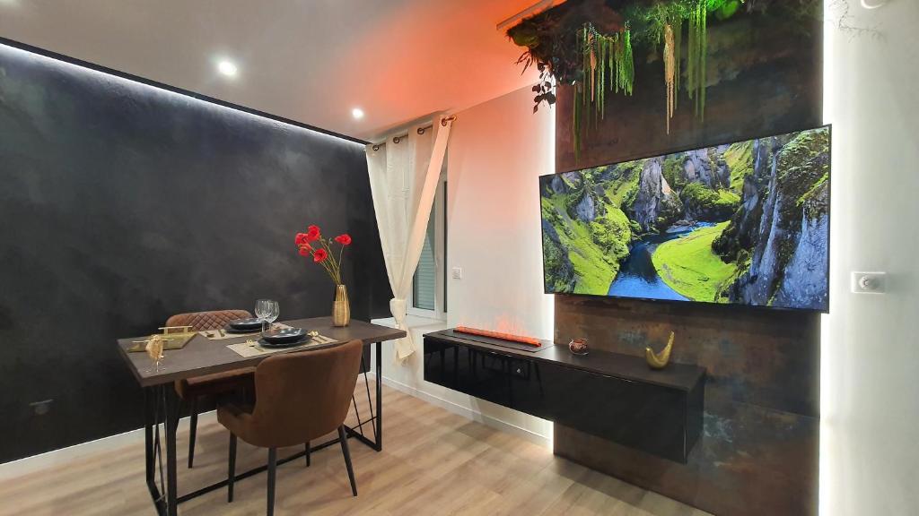 uma sala de jantar com uma mesa e uma grande televisão em Le Vulcano : duplex lounge ! em Vesoul