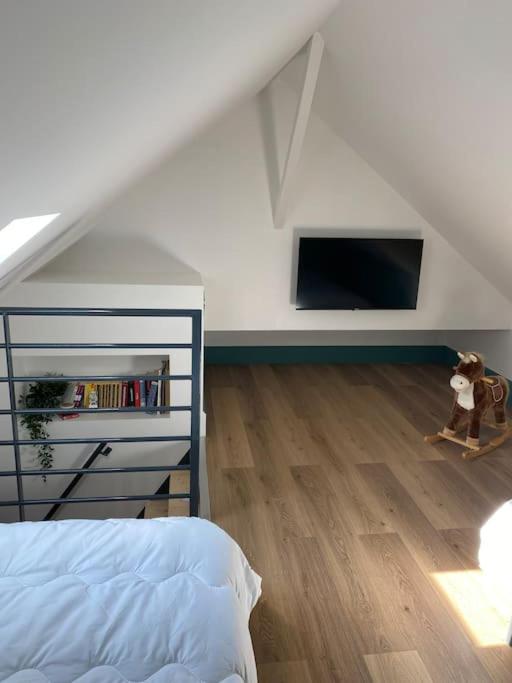 a bedroom with a bed and a tv in the attic at Magnifique villa rénovée avec jaccuzi in Soulac-sur-Mer