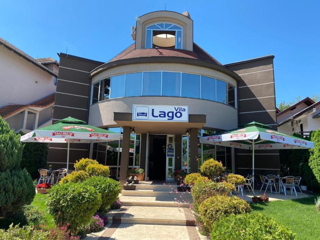 een groot gebouw met tafels en parasols ervoor bij Vila Lago in Veliko Gradište