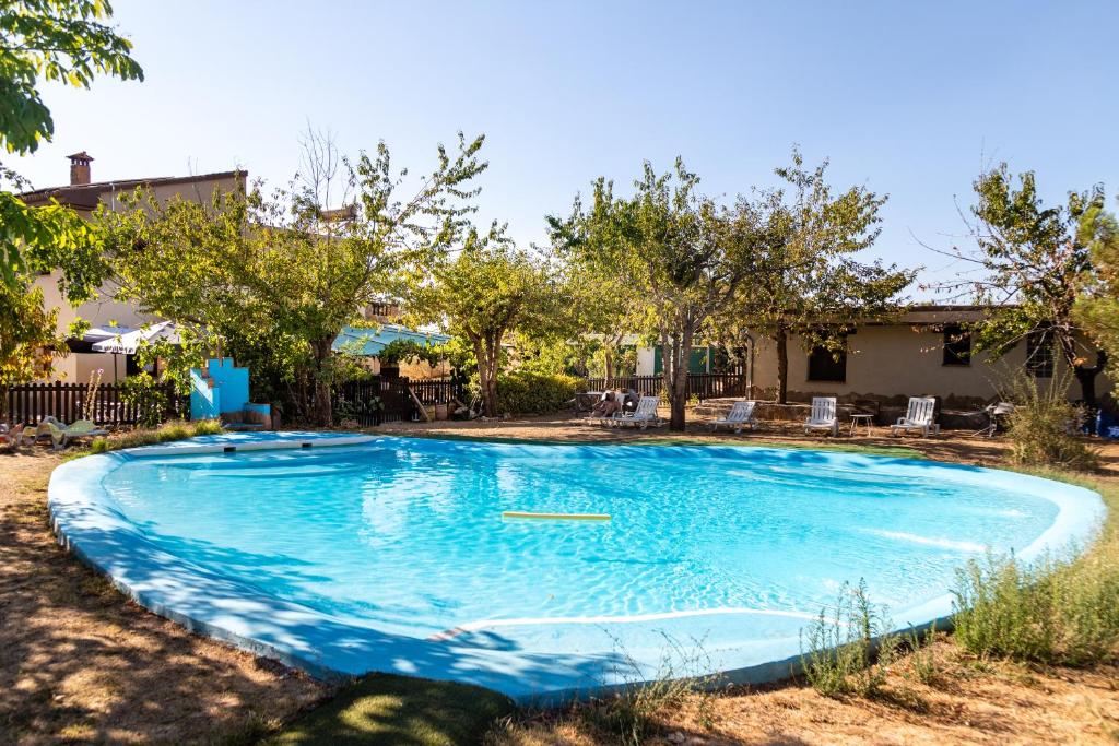 uma grande piscina azul num quintal com árvores em Hotel Rural Fuente La Teja em Güéjar-Sierra