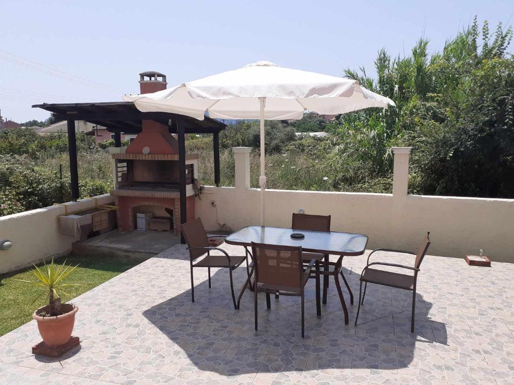 a table and chairs with an umbrella and a grill at Casa Raymo in Kanálion