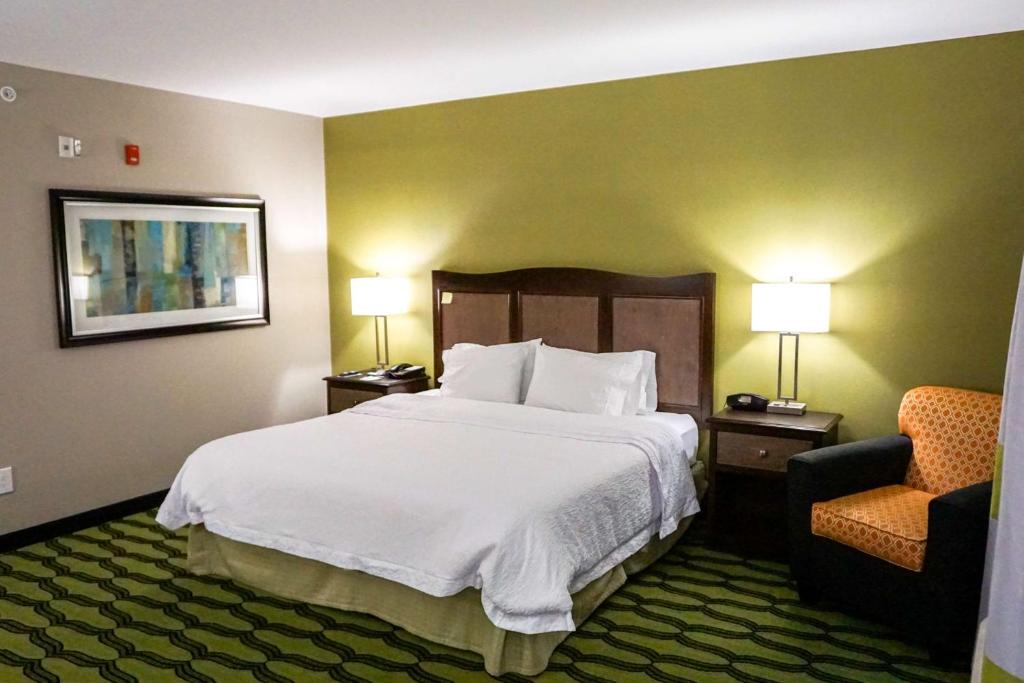 a hotel room with a bed and a chair at Hampton Inn Niagara Falls/ Blvd in Niagara Falls