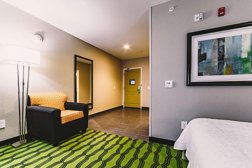 a room with a bed and a chair and a yellow door at Hampton Inn Niagara Falls/ Blvd in Niagara Falls
