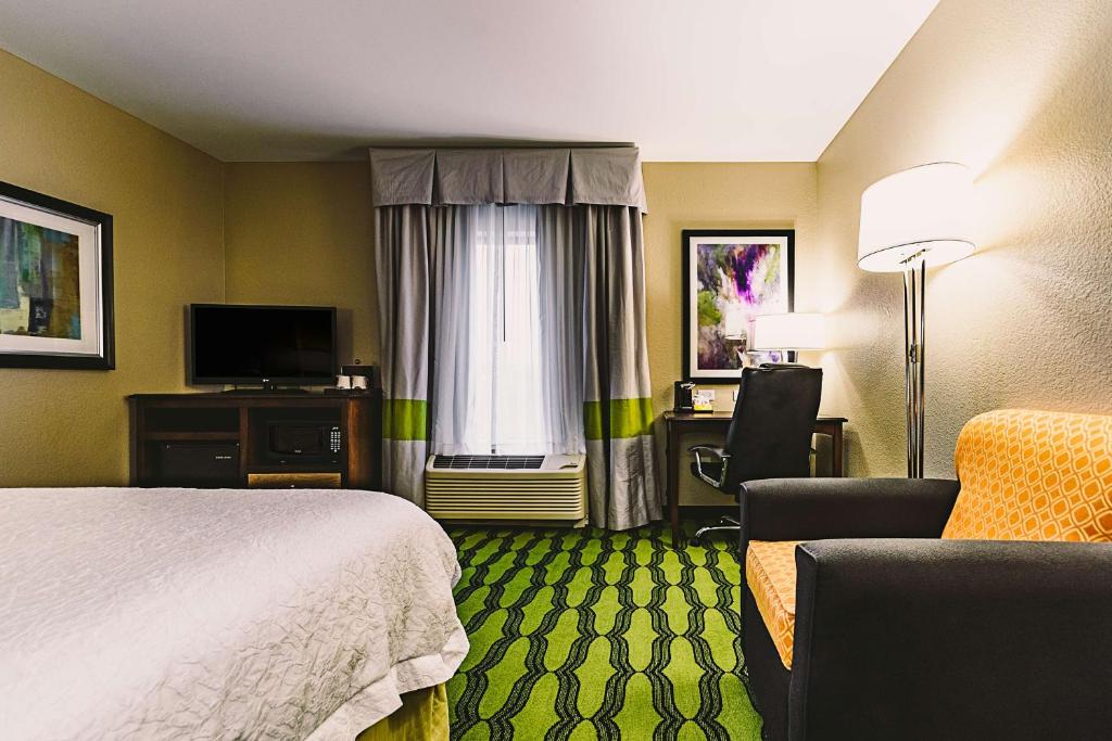 a hotel room with a bed and a chair at Hampton Inn Niagara Falls/ Blvd in Niagara Falls