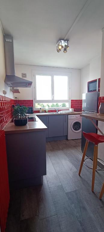 a kitchen with red and white appliances and a red chair at Appart 3 Chambres - 6 personnes - Mémorial - Université in Caen