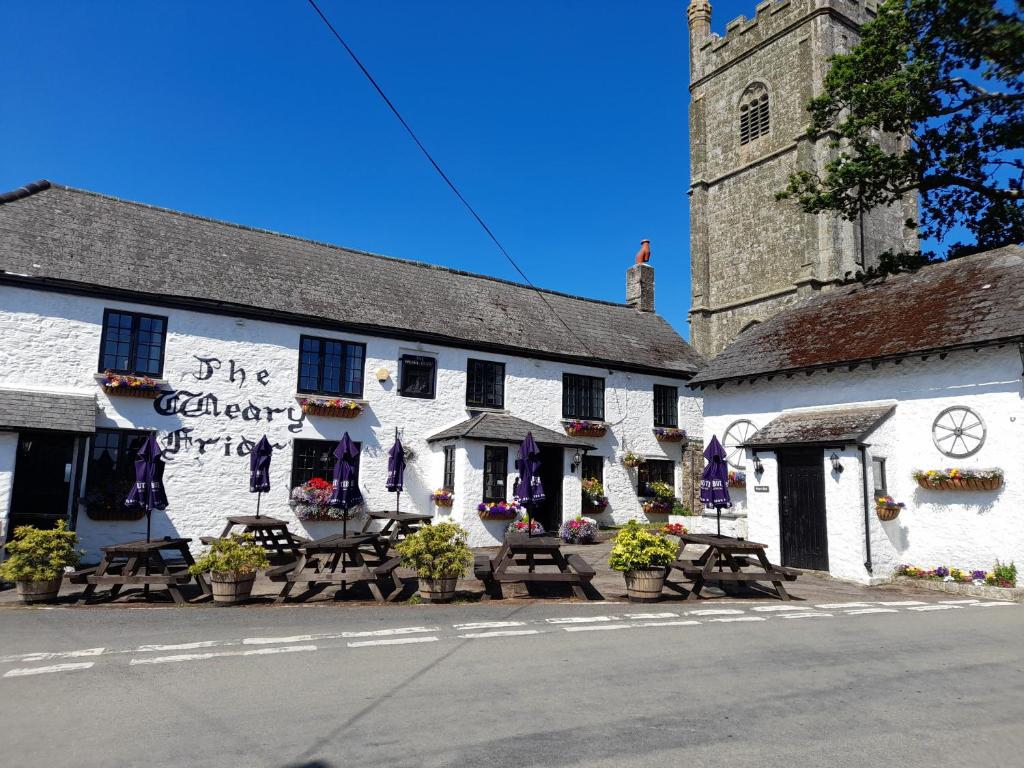 un edificio blanco con mesas y sillas delante en The Weary Friar Inn, en Pillaton