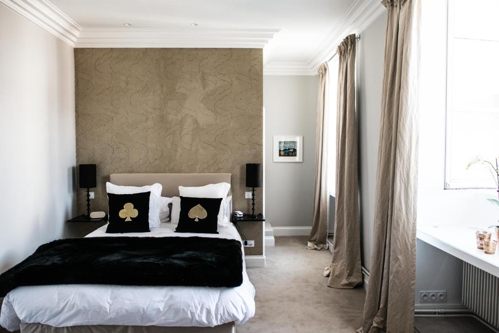 a bedroom with a bed with black and gold pillows at Clarance Hotel Lille in Lille