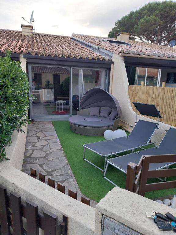 a backyard with a patio furniture and grass at CHARMANTE VILLA HELIOVILLAGE CAMP NATURISTE in Cap d'Agde