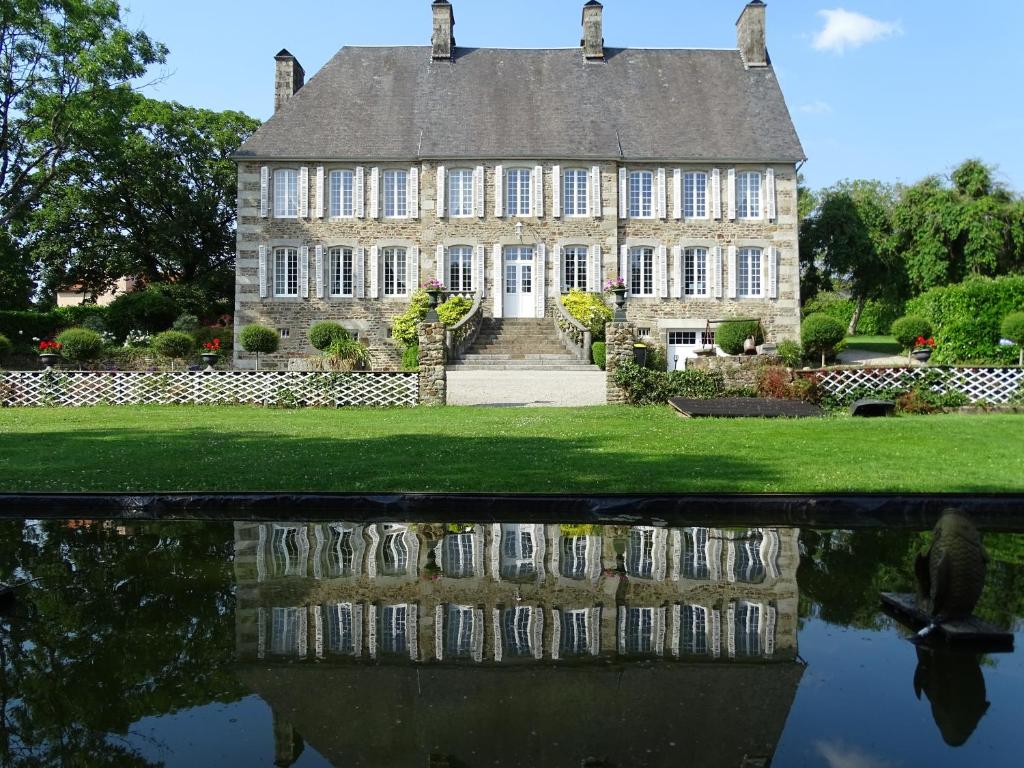 ein altes Haus mit Spiegelung im Wasser in der Unterkunft Manoir Saint Martin in Percy