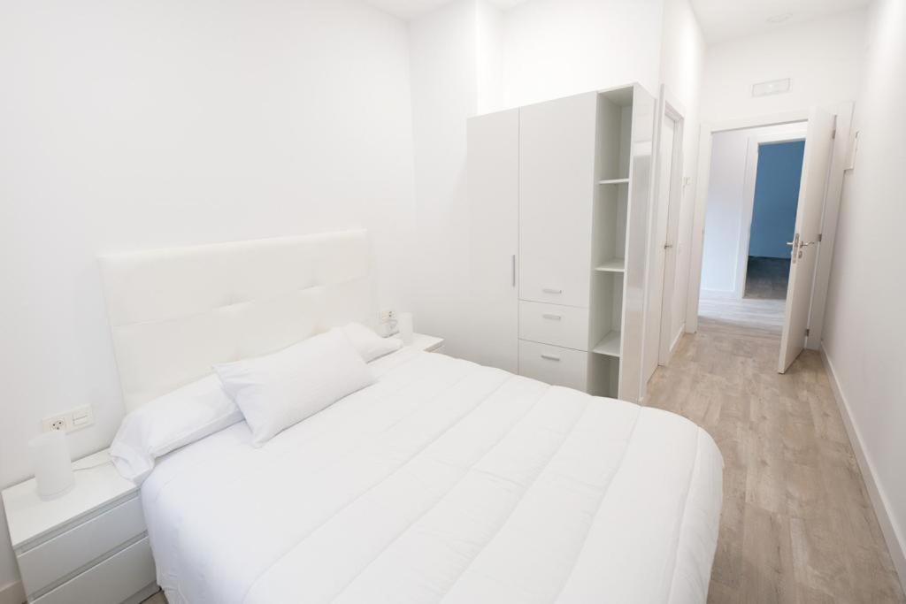 Dormitorio blanco con cama blanca y espejo en Pension MD, en San Sebastián