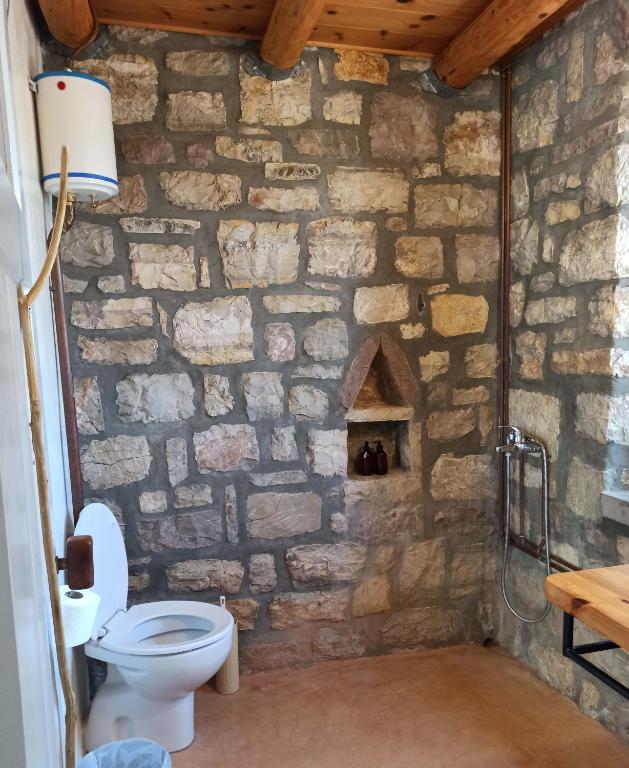 a stone bathroom with a toilet and a stone wall at Kastraki Art Houses in Kousounárion