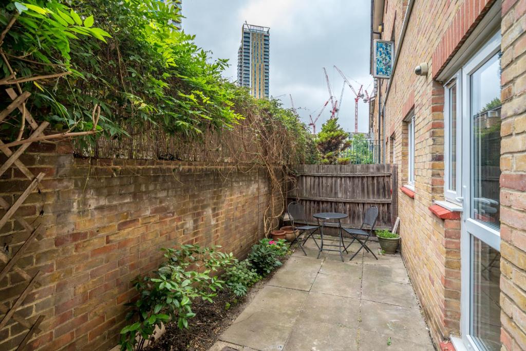 a brick wall with a table and chairs on a sidewalk at ALTIDO Cosy flat in Elephant and Castle, private garden and pets allowed in London