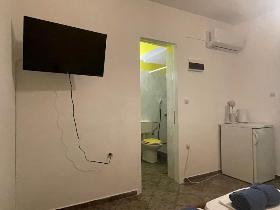 TV de pantalla plana colgada en la pared de un baño en Yellow Beach House, en Logaras