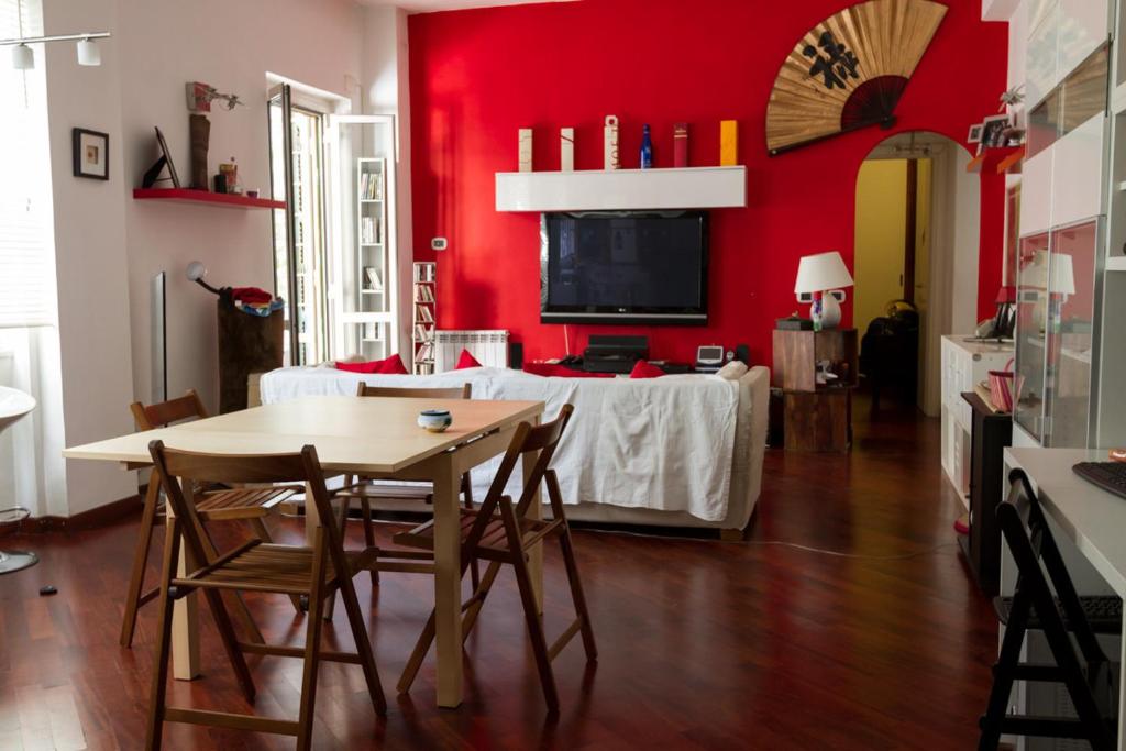 une salle à manger avec une table et un mur rouge dans l'établissement Vacanze Romane con giardino, à Rome