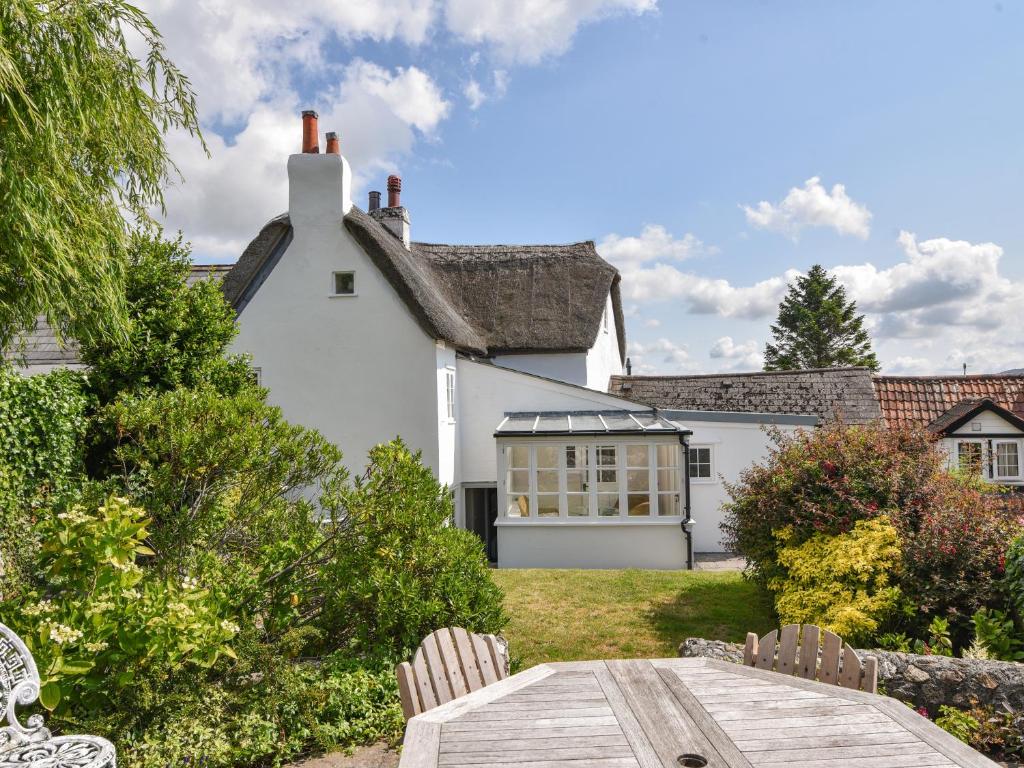 a white house with a table in front of it at Thatched Cottage in Bridport
