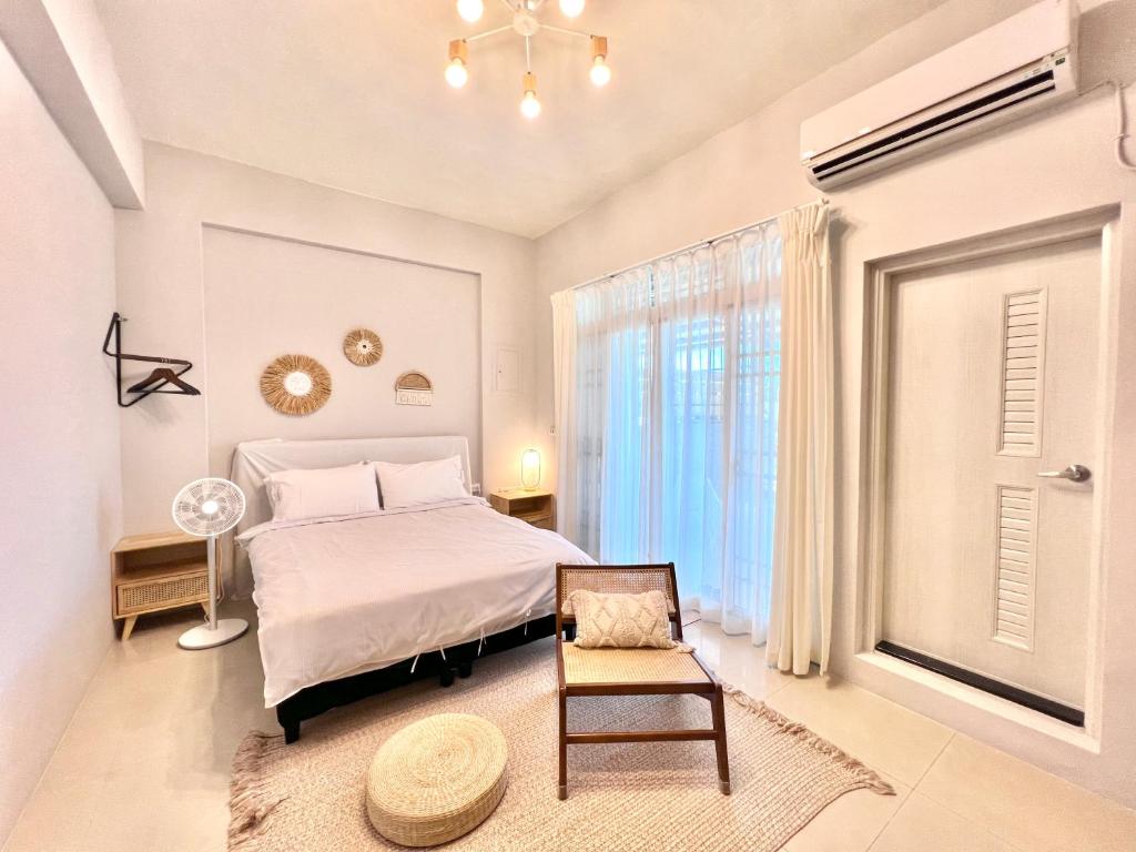 um quarto com uma cama, uma cadeira e uma janela em Brother Homestay em Taitung City
