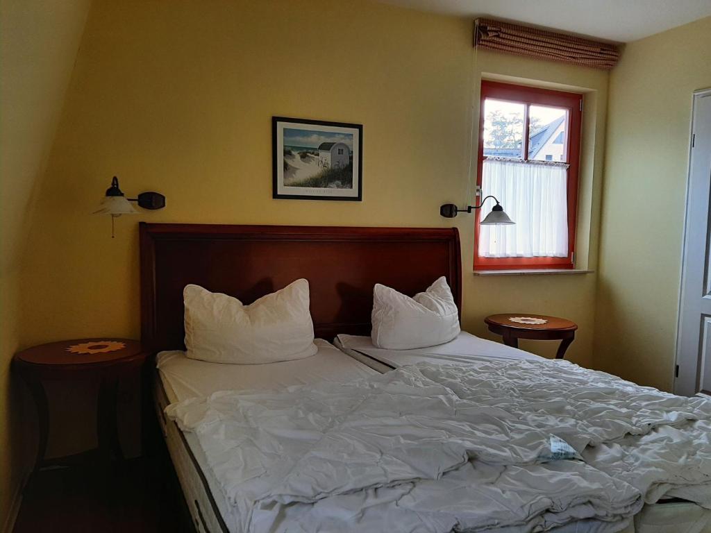 Schlafzimmer mit einem Bett mit weißer Bettwäsche und Kissen in der Unterkunft Residenz Lausitz - Apartments für Urlaub mit Hund in Graal-Müritz