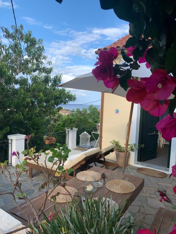 a patio with a table and an umbrella and flowers at Harry's Studios in Gaios