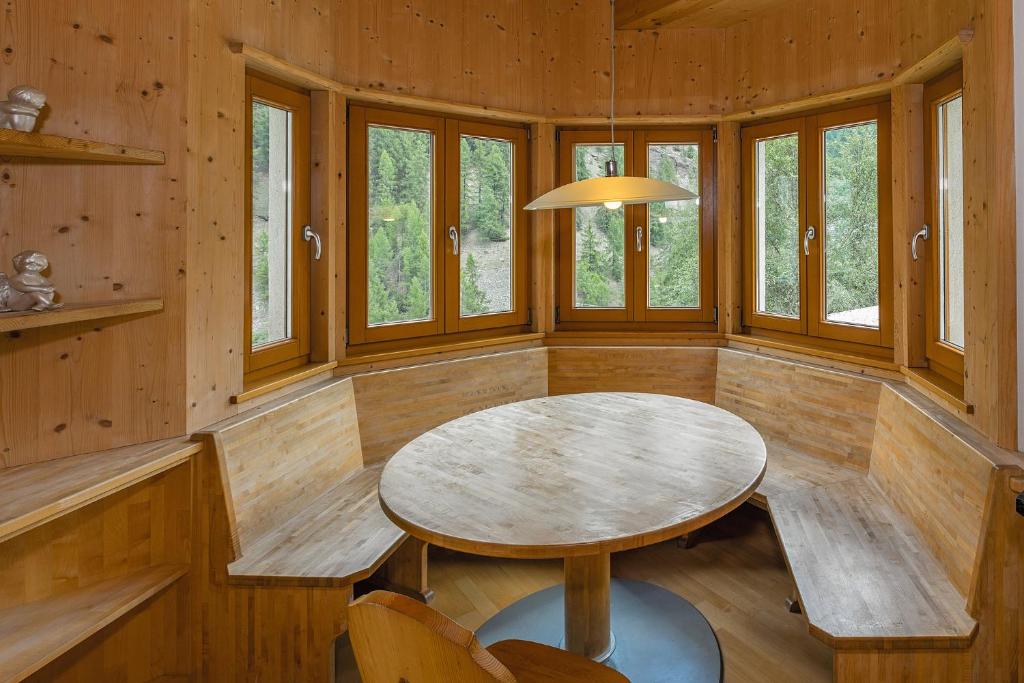 een eetkamer met een tafel, stoelen en ramen bij Brugghof Apartment Brugg in Madonna