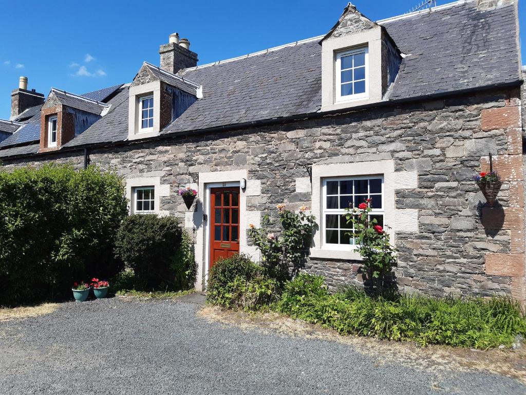 una vieja casa de piedra con una puerta roja en Wyndhead Cottage, en Lauder