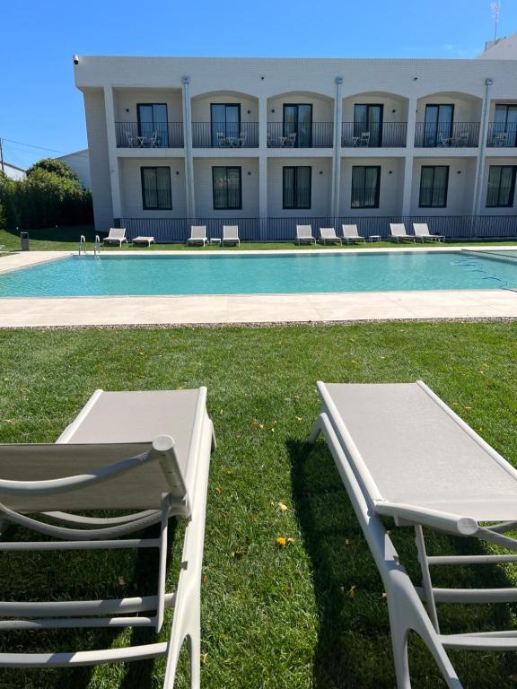 a chair and a table next to a swimming pool at Hotel H4 Cangas 3 Superior in Cangas de Morrazo