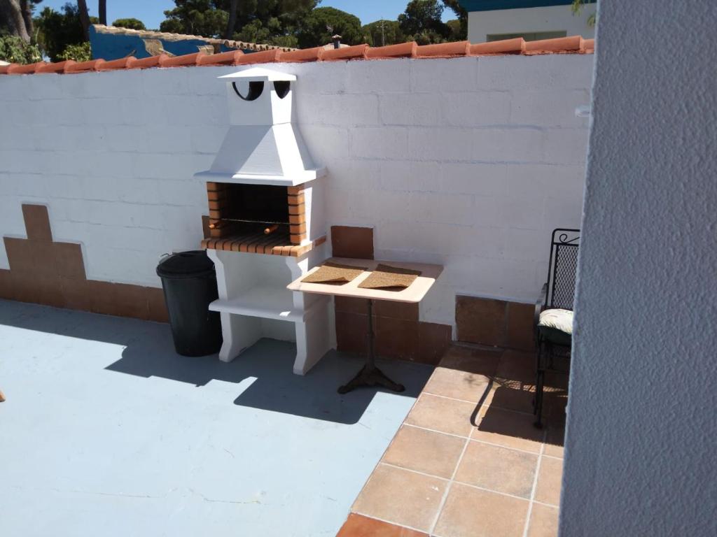 a patio with a grill and a table and a chair at Chalet Aquí No Es in Chiclana de la Frontera