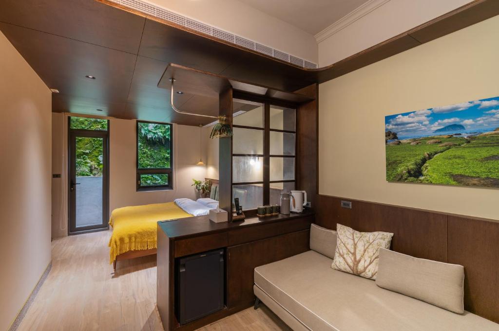 um quarto com uma cama e um sofá num quarto em 安樓文旅Enzo House em Keelung