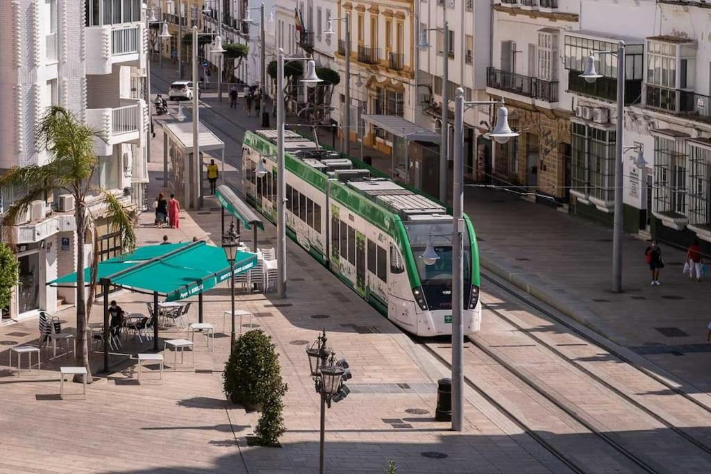 a green and white tram on a city street at Apartamento Céntrico Casa Calana in San Fernando