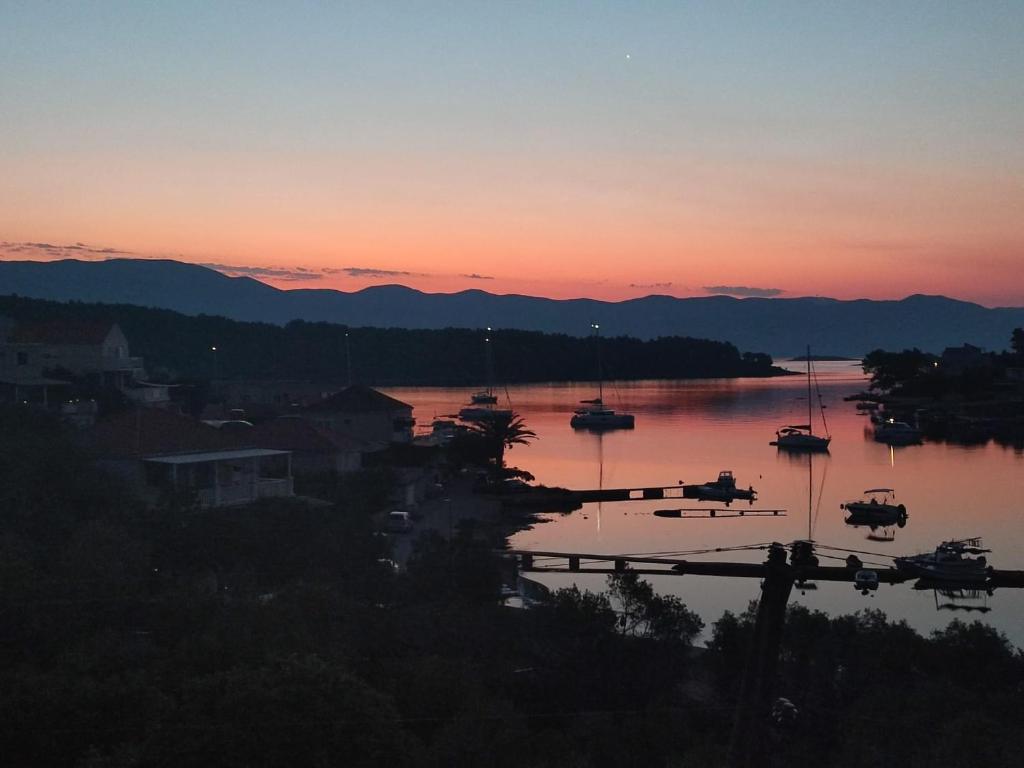 einen Sonnenuntergang über einem Hafen mit Booten im Wasser in der Unterkunft Apartments Marebella in Lumbarda