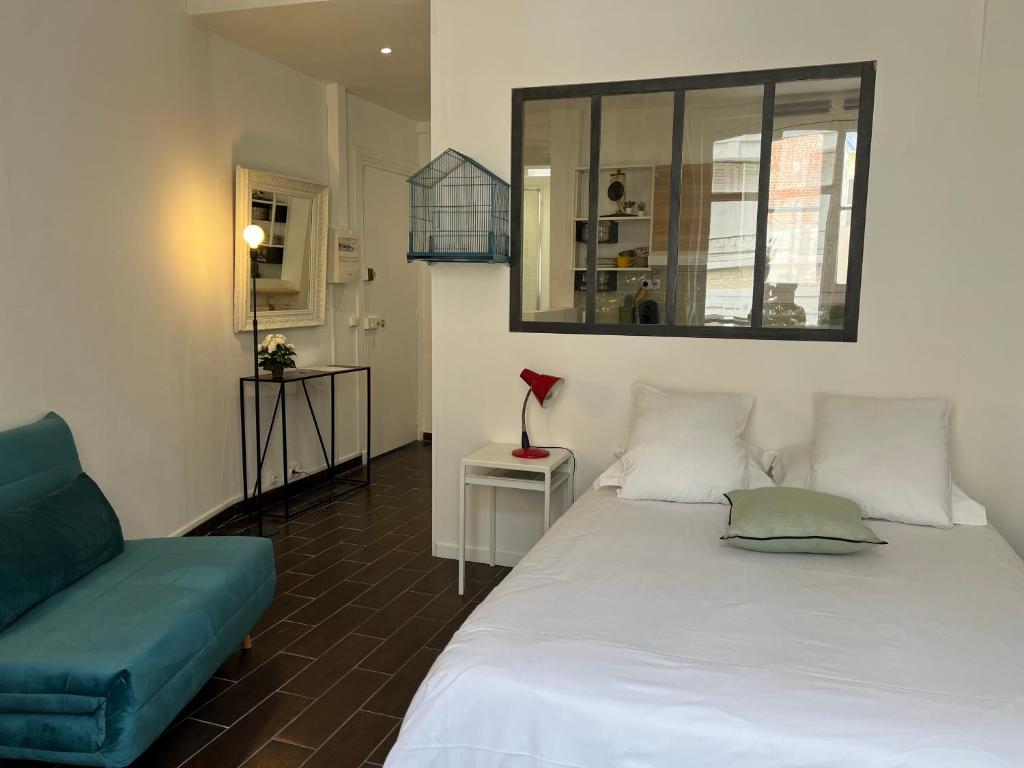 een slaapkamer met een wit bed en een blauwe bank bij Studio de la Maison de la Plage à 150 m de la plage " Chez Anne à la plage" in Trouville-sur-Mer