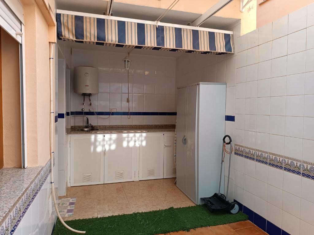 ein Badezimmer mit einem Kühlschrank und grünem Boden in der Unterkunft El Roalico in Los Alcázares