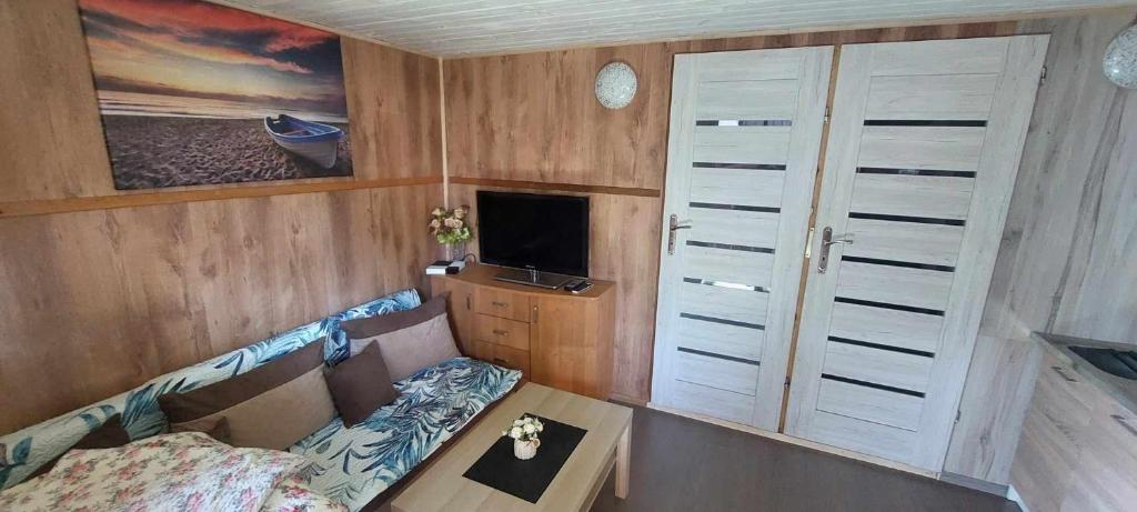 a small room with a couch and a tv at Mały domek w centrum Rowów in Rowy