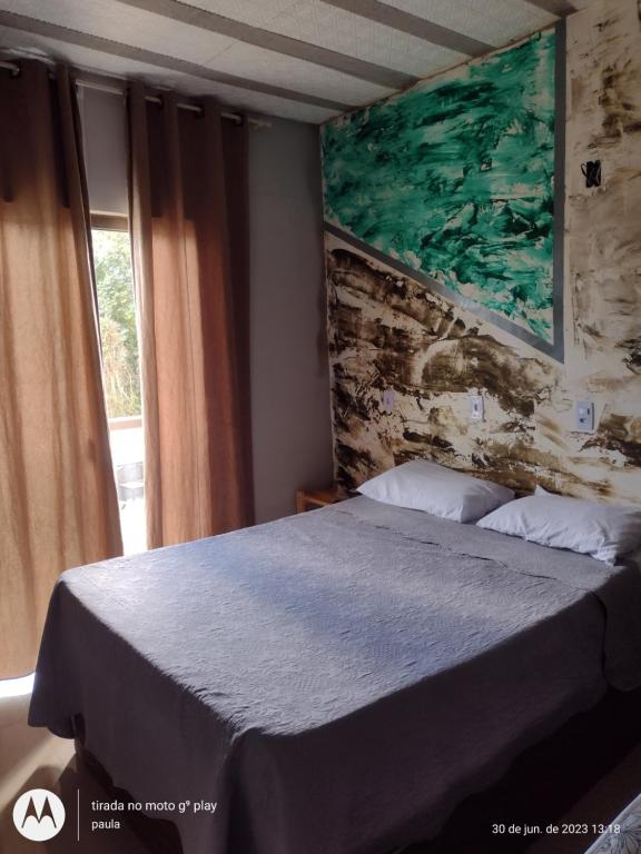 a bedroom with a bed and a painting on the wall at Recanto Serra Monte in Caparaó Velho