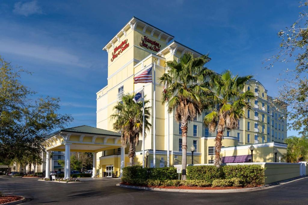 a hotel building with palm trees in front of it at Hampton Inn & Suites Jacksonville Deerwood Park in Jacksonville