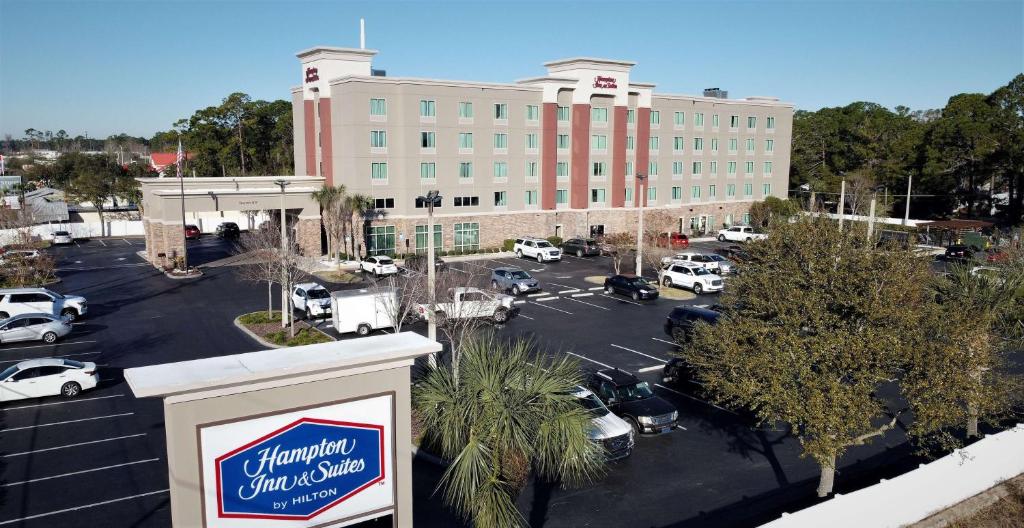Hampton Inn & Suites Jacksonville Beach Boulevard/Mayo Clinic في جاكسونفيل: علامة أمام مبنى كبير مع موقف للسيارات