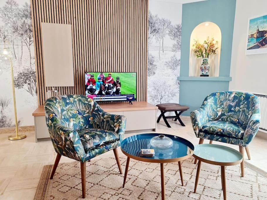 a living room with two chairs and a tv at Appartement spacieux centre ville et plage à pied in Concarneau