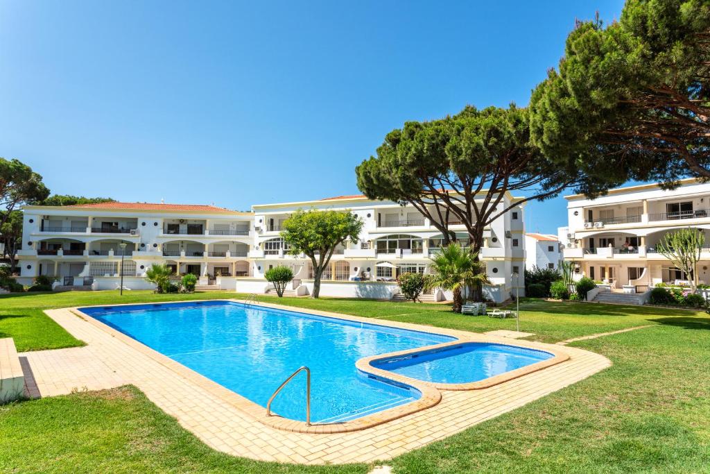 a swimming pool in front of a large apartment building at Host Wise - Amazing Sunny Flat - Swimming Pool & Terrace in Vilamoura
