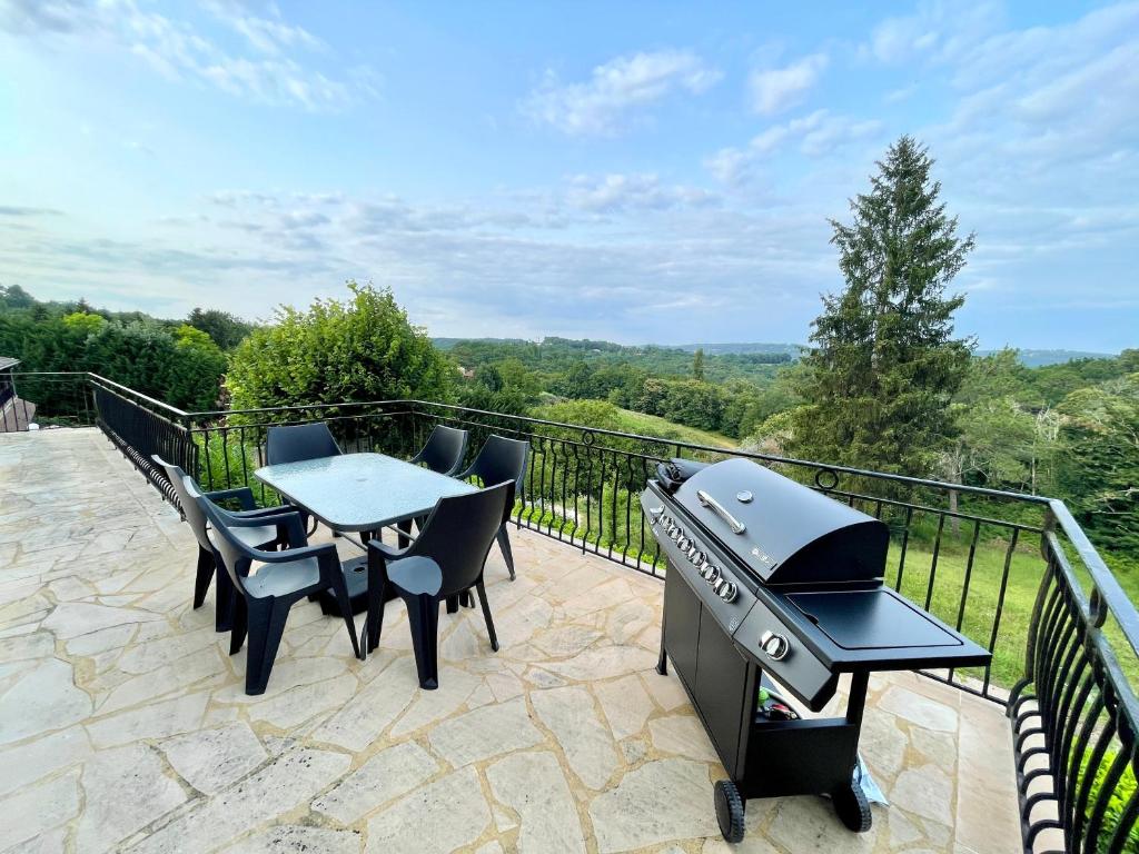 - un barbecue, des tables et des chaises sur la terrasse dans l'établissement Maison avec Terrasse Surplombant la Vallée, à Sarlat-la-Canéda
