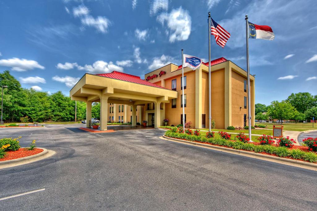 a hotel with two american flags on a road at Hampton Inn Laurinburg in Laurinburg