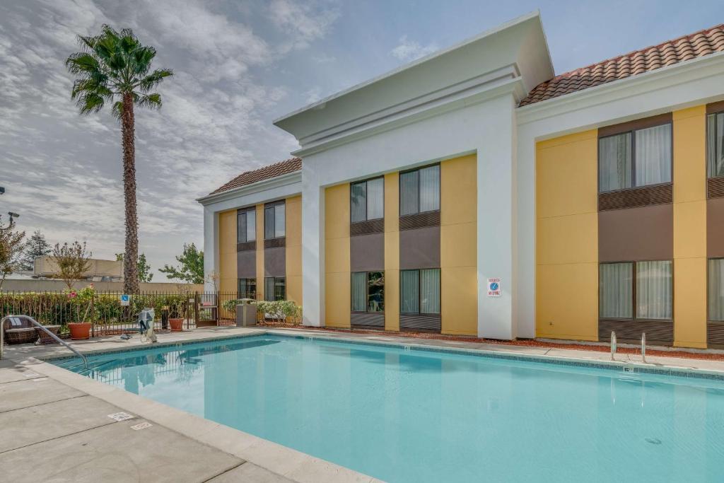 a swimming pool in front of a building with a palm tree at Hampton Inn Livermore in Livermore