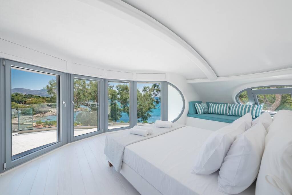 - une chambre blanche avec un grand lit et des fenêtres dans l'établissement Villa Tholos -Athens Riviera, à Kalívia Thorikoú