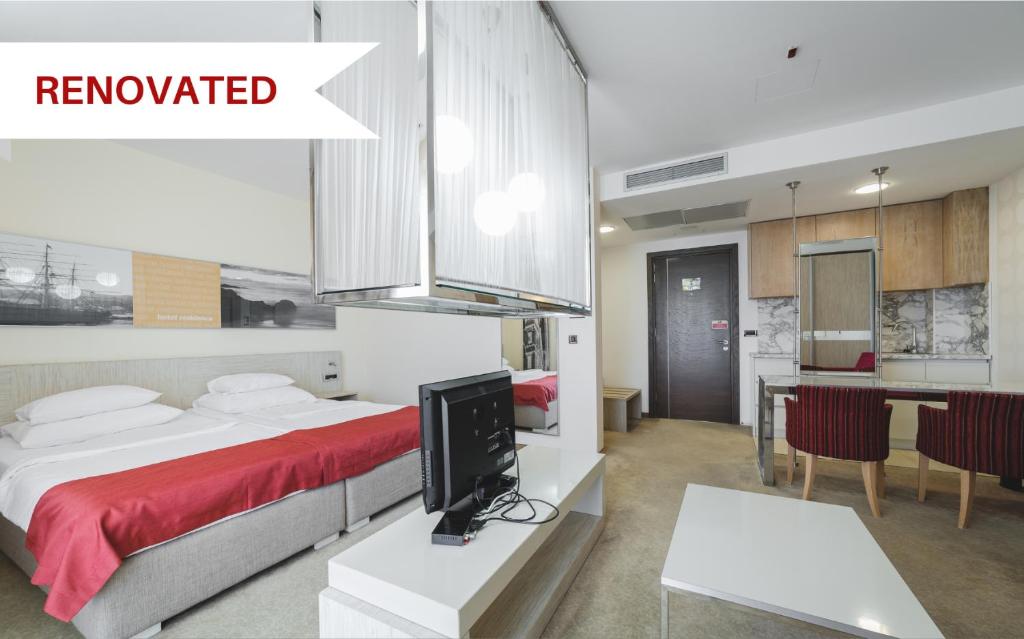 a bedroom with a bed and a tv and a kitchen at Hotel & Apartments HEC Residence in Sveti Stefan