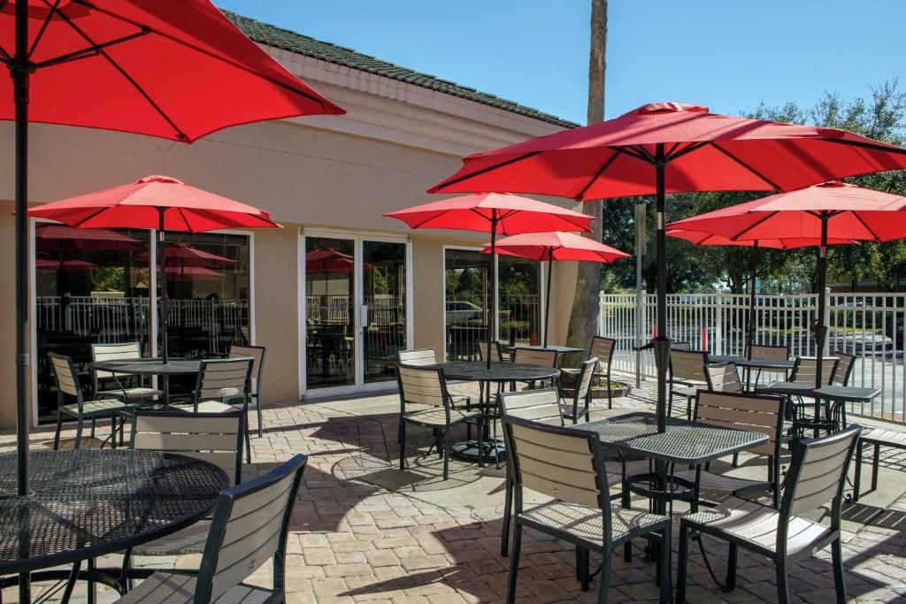 un groupe de tables et de chaises avec des parapluies rouges dans l'établissement Hampton Inn Lake Buena Vista / Orlando, à Orlando