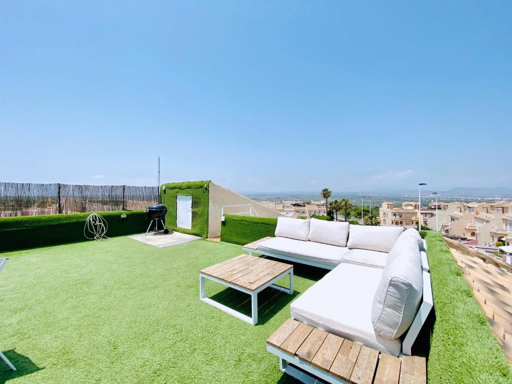 a patio with a white couch and a table on a roof at Casa Natura Sunset Beach in Gran Alacant