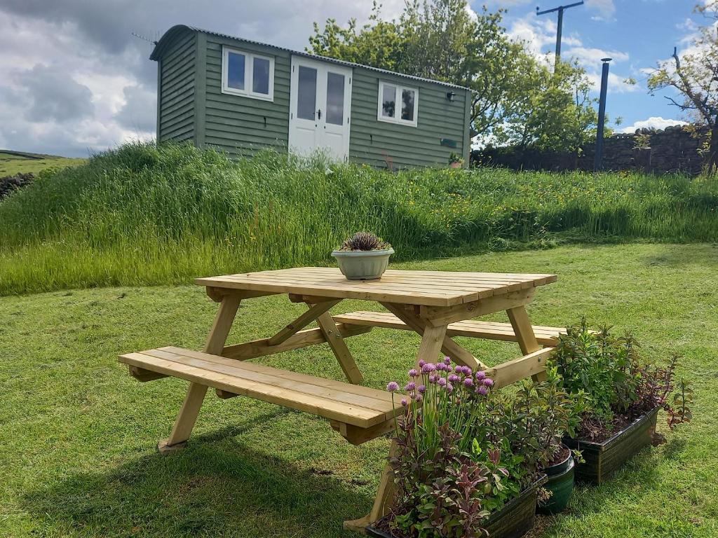 a picnic table in a yard with a house in the background at The Journeyman Luxury Shepherds Hut in Barnoldswick