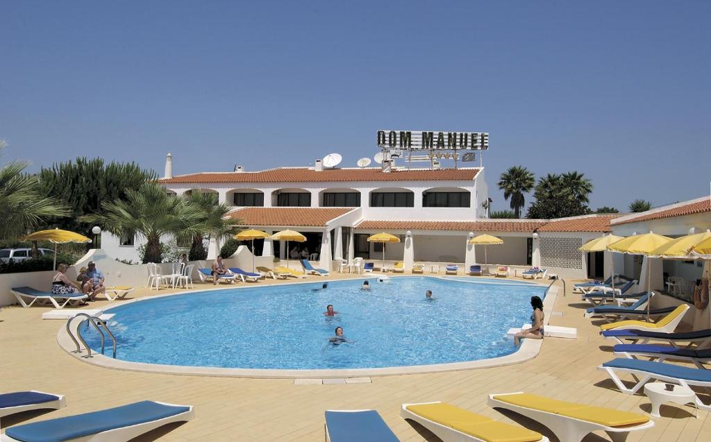 une grande piscine avec des chaises longues et un hôtel dans l'établissement Albergaria Dom Manuel Hotel, à Porches